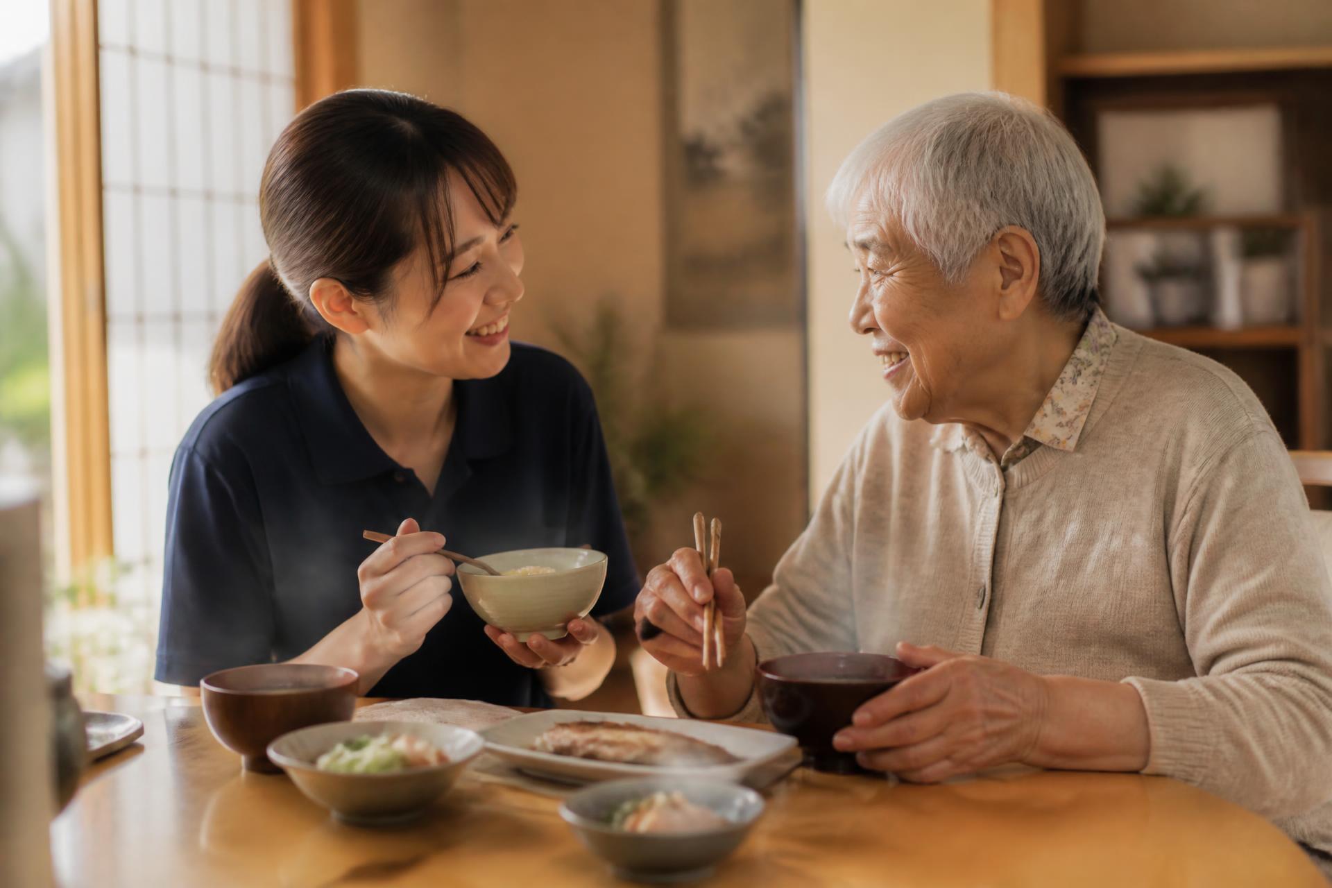 あたたかい食卓で笑い合う利用者様とスタッフ